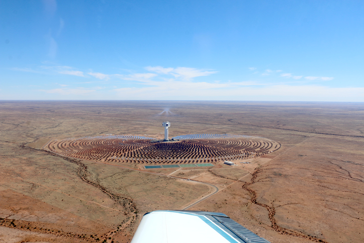 A bird's eye view of solar power plant with several panels and a large tower in a desert environment.